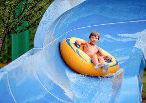 Garçon qui descend d'un tobogan bleu dans une bouée jaune