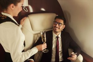 Homme qui voyage en première classe dans un avion et une hôtesse de l'air qui lui sert une coupe de champagne