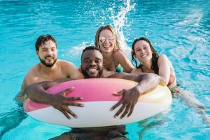 deux jeunes hommes et deux jeunes femmes qui sourient en groupe dans une piscine