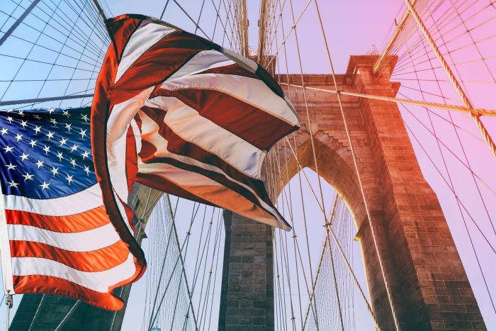 United States Flag at top of Brooklyn Bridge. There is a deep blue sky on background, on foreground there are all the wires of the bridge. Patriotism concept. Pont de New York et drapeau américain qui flotte