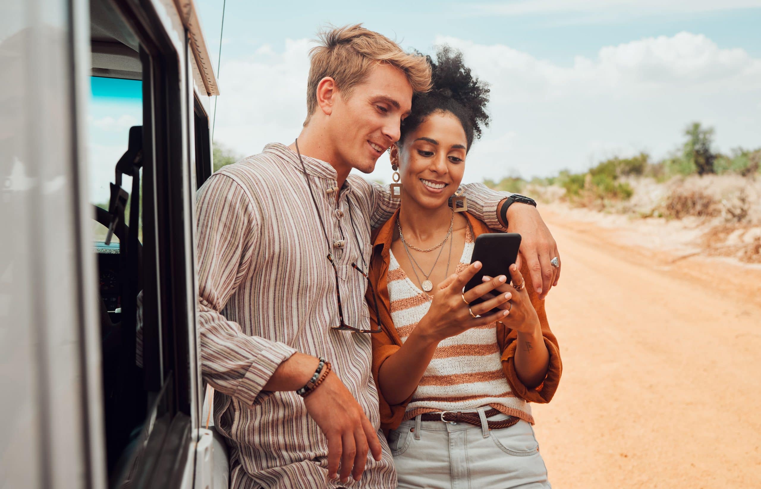 couple en voyage Couple en vacances près d'une voiture, regardant téléphone portable