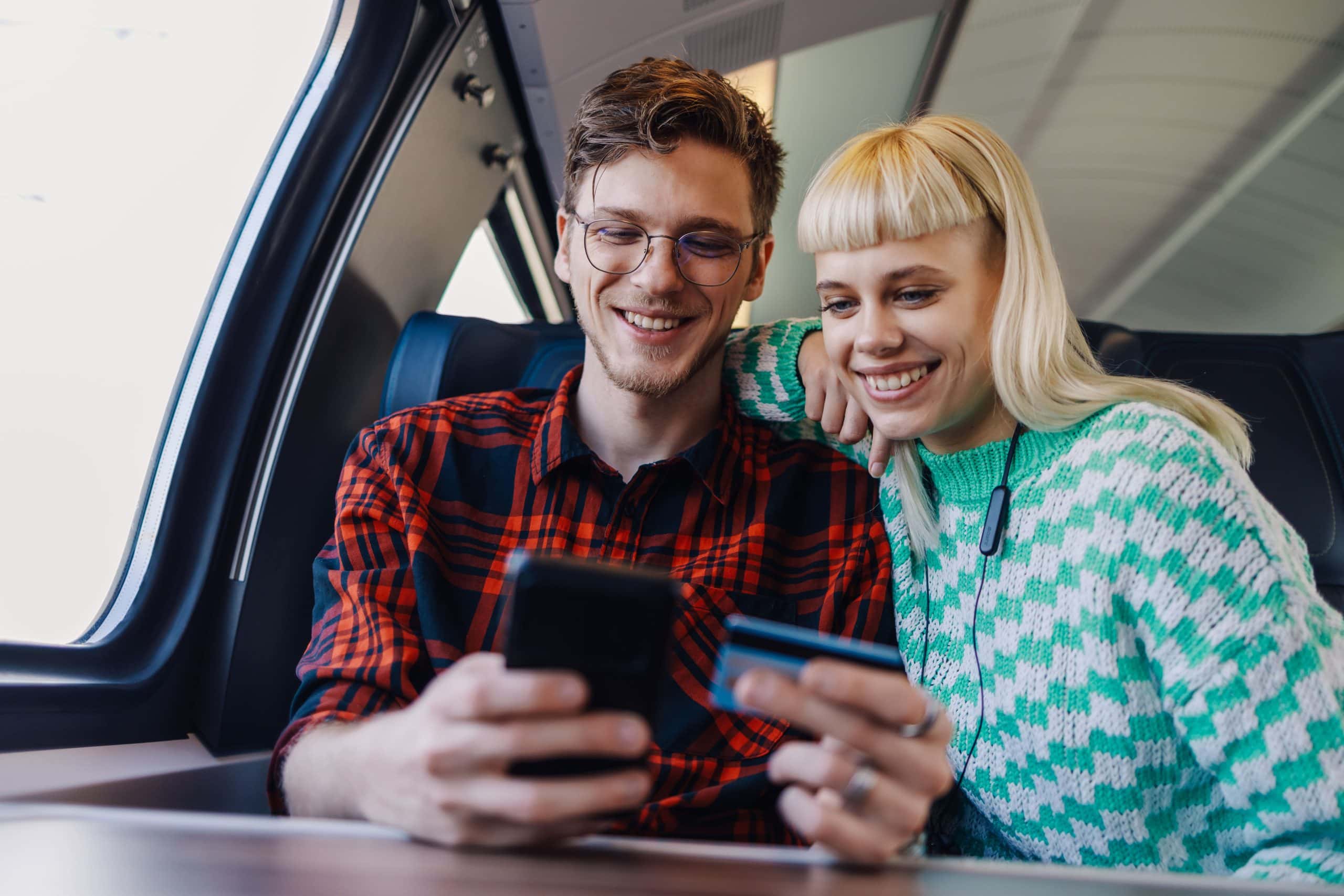 voyageurs avec natel Jeune couple dans un train entrain de consulter un natel